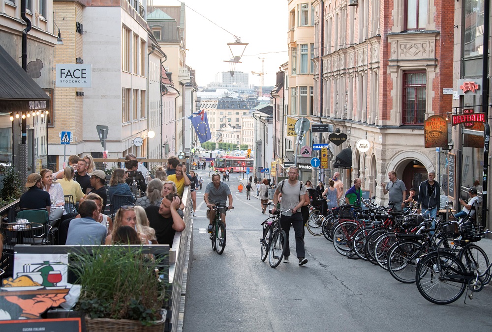 People with bicycles pass by an outdoor restaurant on a street in the Sodermalm neighborhood of Stockholm August 20, 2020. u00e2u20acu201d Picture by Fredrik Sandberg/TT News Agency via Reuters