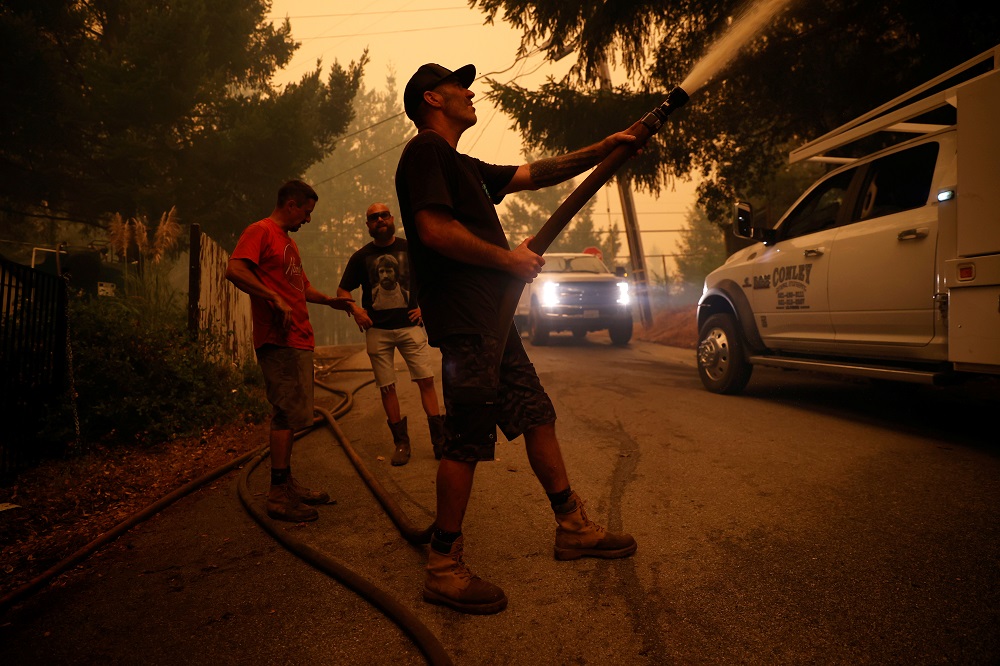 Dave Broome, who is among a group of friends who call themselves u00e2u20acu0153Rescue Oneu00e2u20acu009d, douses water on a structure during the CZU Lightning Complex Fire on the outskirts of Santa Cruz August 20, 2020. u00e2u20acu201d Reuters pic