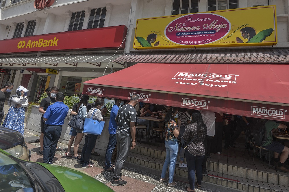 People are seen disregarding social distancing rules while waiting at the entrance of Sri Nirwana Maju banana leaf restaurant in Bangsar August 1, 2020. — Picture by Shafwan Zaidon