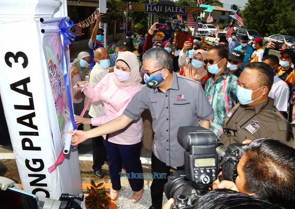 Fadillah (second right) unveiling the Merdeka@Komunity Programme at Lorong Piala 3 banner upon his arrival, accompanied by Sharifah (left) and Information Department Sarawak director Suwadi Guliling (right).  u00e2u20acu201d  Borneo Post Online pic