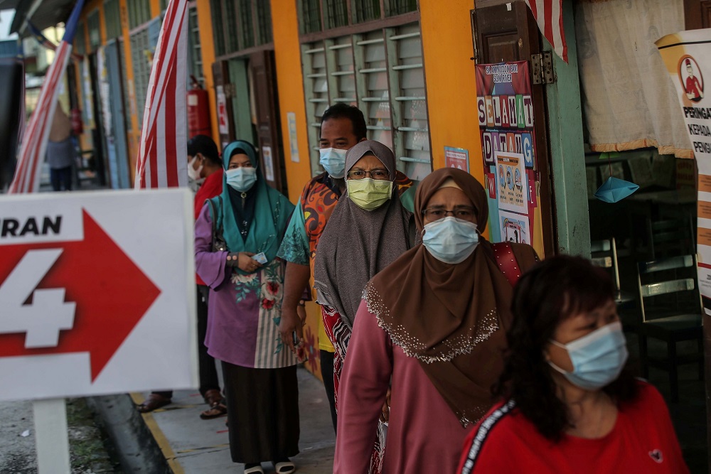 People are seen practising social distancing while waiting in line to cast their ballots at the Sekolah Kebangsaan Aminnudin Baki polling station in Slim River August 29, 2020. — Picture by Farhan Najib