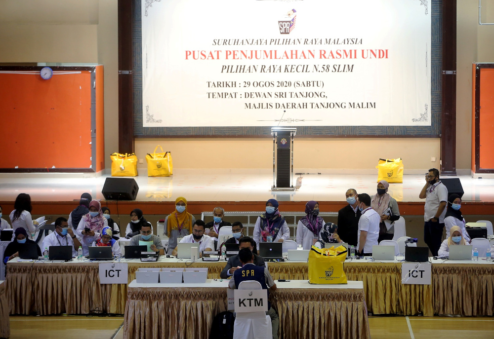 Election Commission (EC) officers bring Slim by-election ballot boxes to the vote-tallying centre at the Dewan Sri Tanjung in Tanjung Malim August 29, 2020. — Picture by Farhan Najib