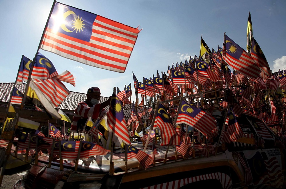Taza Alang Rahim, 60, adjusts the Jalur Gemilang on his fully decorated Proton Saga Aeroback in Ipoh August 28, 2020. u00e2u20acu201d Bernama pic