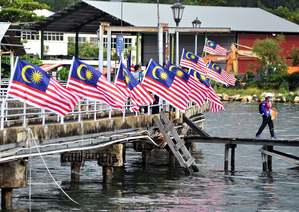 A man walks past a row of Jalur Gemilang which has been put up in conjunction with the Merdeka celebrations, in Labuan August 30, 2020. u00e2u20acu201d Bernama pic