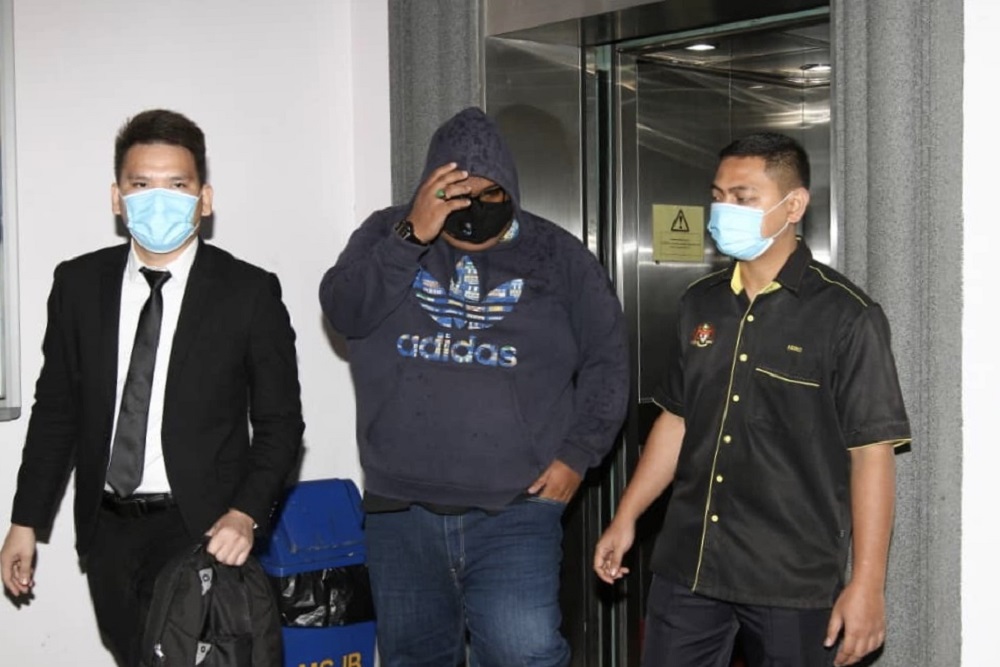 Policeman Mohd Yusri Borhan (centre) pleaded not guilty at the Johor Baru Sessions Court today to two charges of soliciting and receiving bribes worth RM3,500 more than four years ago. u00e2u20acu201d Picture by Ben Tan
