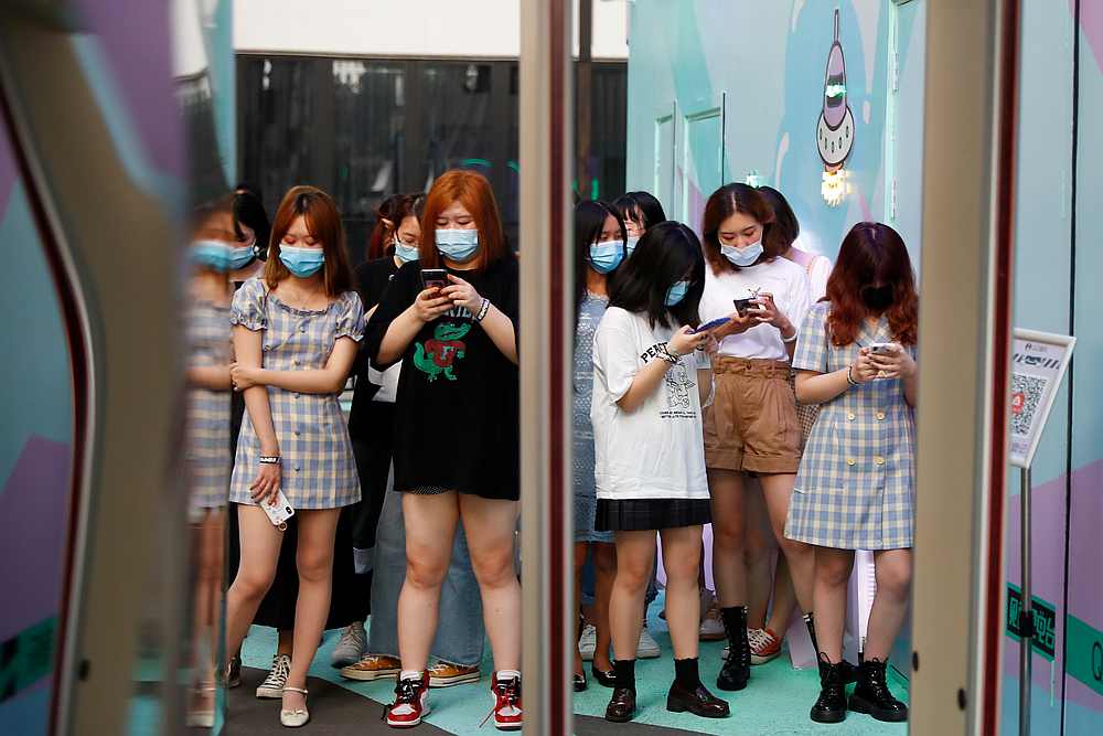 People use their phones as they wait for the start of a promotion event by the QQ Music streaming service, following a Covid-19 outbreak in Beijing, China August 6, 2020. u00e2u20acu201d Reuters pic