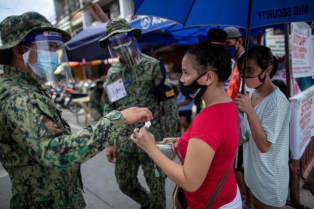 Police officers check a woman's quarantine pass at a checkpoint amid the reimposed strict lockdown to curb Covid-19 infections, in Manila, Philippines August 17, 2020. u00e2u20acu201d Reuters pic