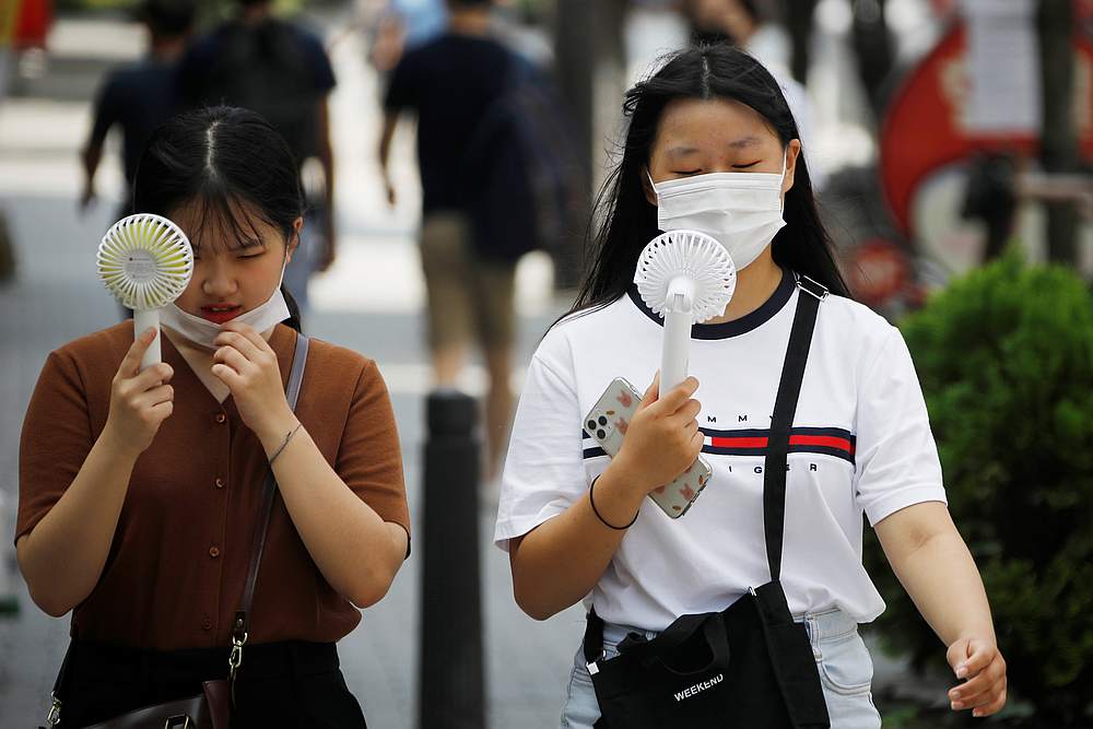 Women wearing masks to prevent the spread of the Covid-19 use portable fans to cool down in Seoul, South Korea August 20, 2020. u00e2u20acu201d Reuters pic
