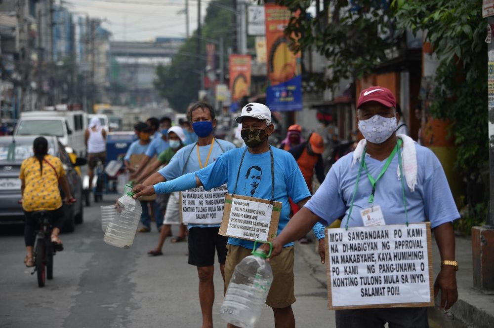 In this photo taken on August 12, 2020, a group of jeepney drivers with placards strapped along their bodies with writings u00e2u20acu02dcMam/sir, weu00e2u20acu2122re jeepney drivers, asking for your helpu00e2u20acu2122, beg for alms along a road in Manila. u00e2u20acu201d AFP pic
