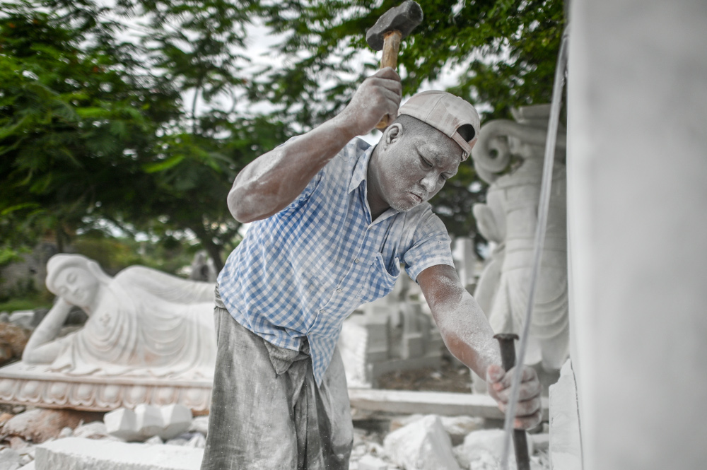 This photo taken June 21, 2020 shows a worker cutting a block of marble for a statue in Sagyin village in Madaya township, about 46km from Mandalay. — AFP pic
