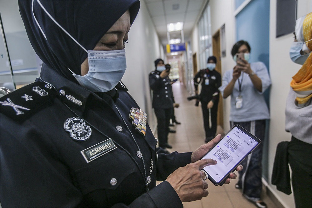 Asmawati holds up her mobile phone to show her self-sampling cervical cancer screening results. 