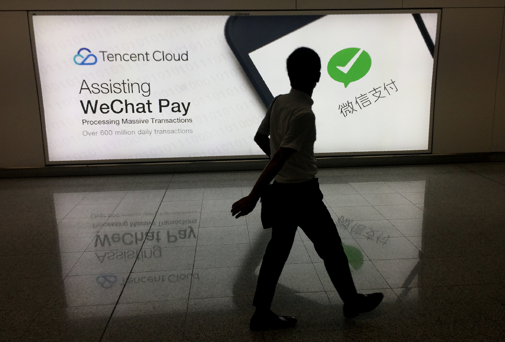 This file photo taken August 21, 2017 shows a man walking at Hong Kongu00e2u20acu2122s international airport past an advertisement for the WeChat social media platform owned by Chinau00e2u20acu2122s Tencent company. u00e2u20acu201d AFP pic