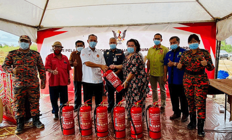 Penguang (centre left) hands over fire extinguishers to longhouse chieftain Patricia Indit, witnessed by Bomba Miri chief Law Poh Kiong (centre) and others. u00e2u20acu201d Borneo Post Online pic