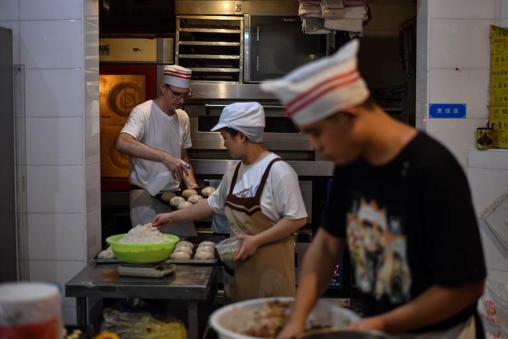 This photo taken on September 8, 2020 shows Uwe Brutzer (back left) working with hearing-impaired employees at his bakery in the city of Changsha. u00e2u20acu201d AFP pic