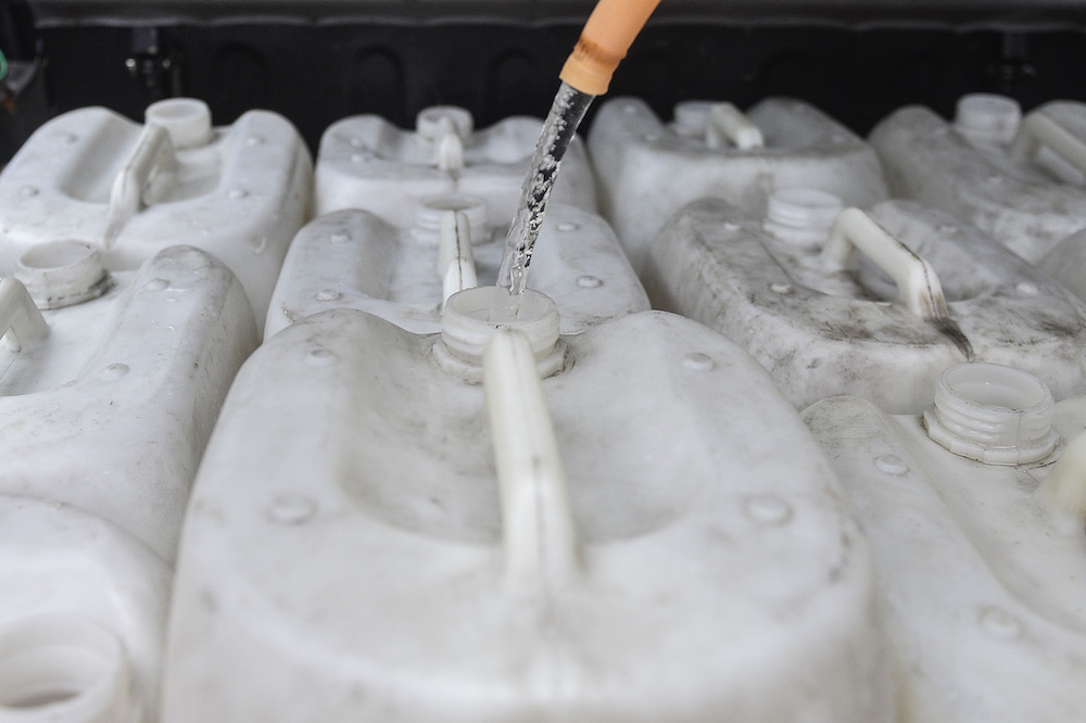 Workers from Restoran Kaya in Puchong Perdana preparing to carry large containers of water into their establishment. u00e2u20acu201d Picture by Miera Zulyana.