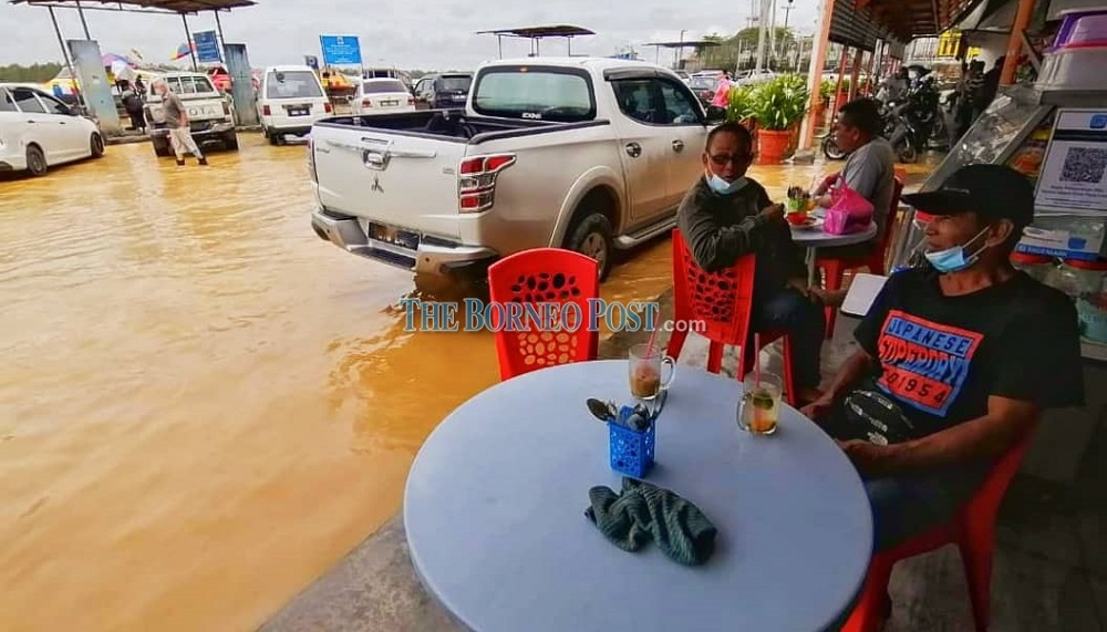 A coffee shop patron stares at the inundated Jalan Khoo Peng Loong in Sibu. u00e2u20acu201d Borneo Post Online pic