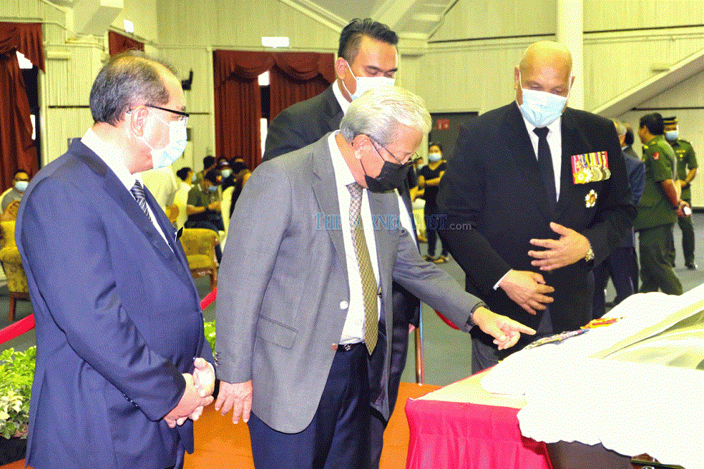 Masing (second left) and Jaul (left) pay their last respects to Awang. u00e2u20acu201d Borneo Post Online pic