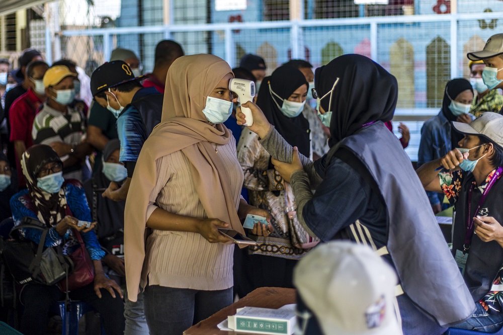 Voters get their temperatures checked before heading to the polling booths to cast their votes at SK Pulau Gaya September 26, 2020. u00e2u20acu201d Picture by Firdaus Latif