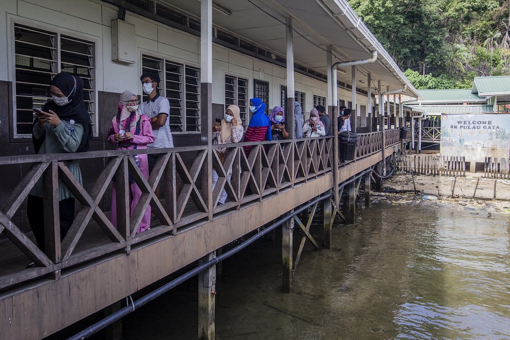 Voters wearing protective masks queue up to cast their votes during the Sabah state election in SK Pulau Gaya September 26, 2020. 