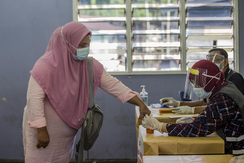 A voter gets her finger marked with indelible ink at the voting station located at SK Pulau Gaya September 26, 2020. u00e2u20acu201d Picture by Firdaus Latif