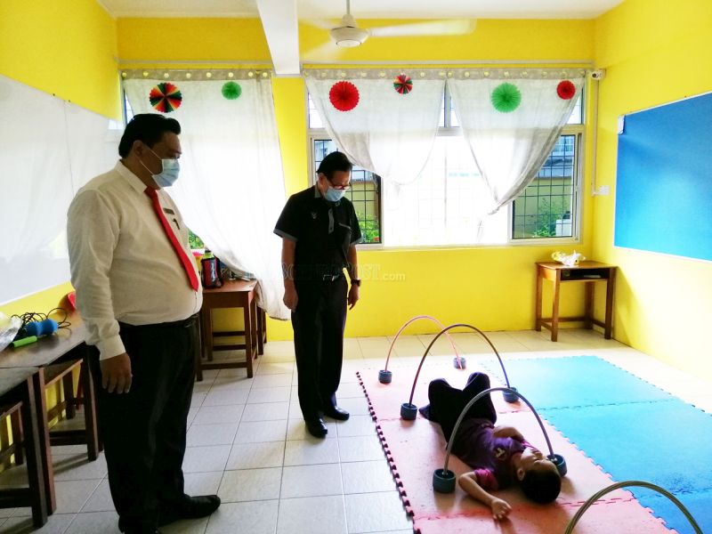 Lai (left) shows Lee how special education classes are conducted. u00e2u20acu201d Borneo Post pic
