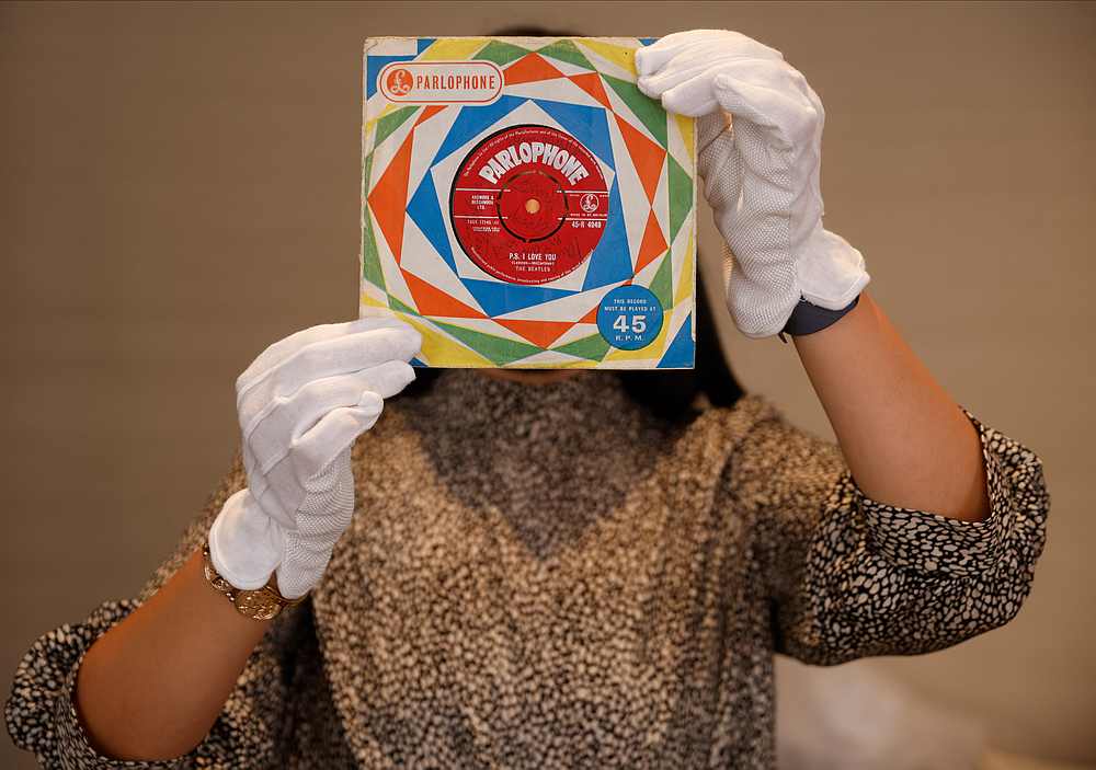 A staff member with a first pressing of the record 'Love Me Do' signed by all four Beatles at Sotheby's auction house ahead of 'Beatles for Sale' auction in London, Britain September 25, 2020. u00e2u20acu201d Reuters pic