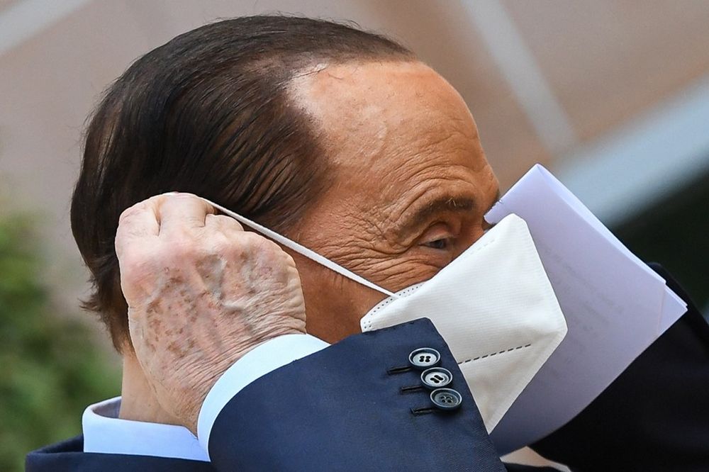 Former Italian prime minister Silvio Berlusconi takes off his mask as he prepares to address the media, as he leaves the San Raffaele Hospital in Milan, September 14, 2020 after he tested positive for coronavirus and was hospitalised since September 3. 