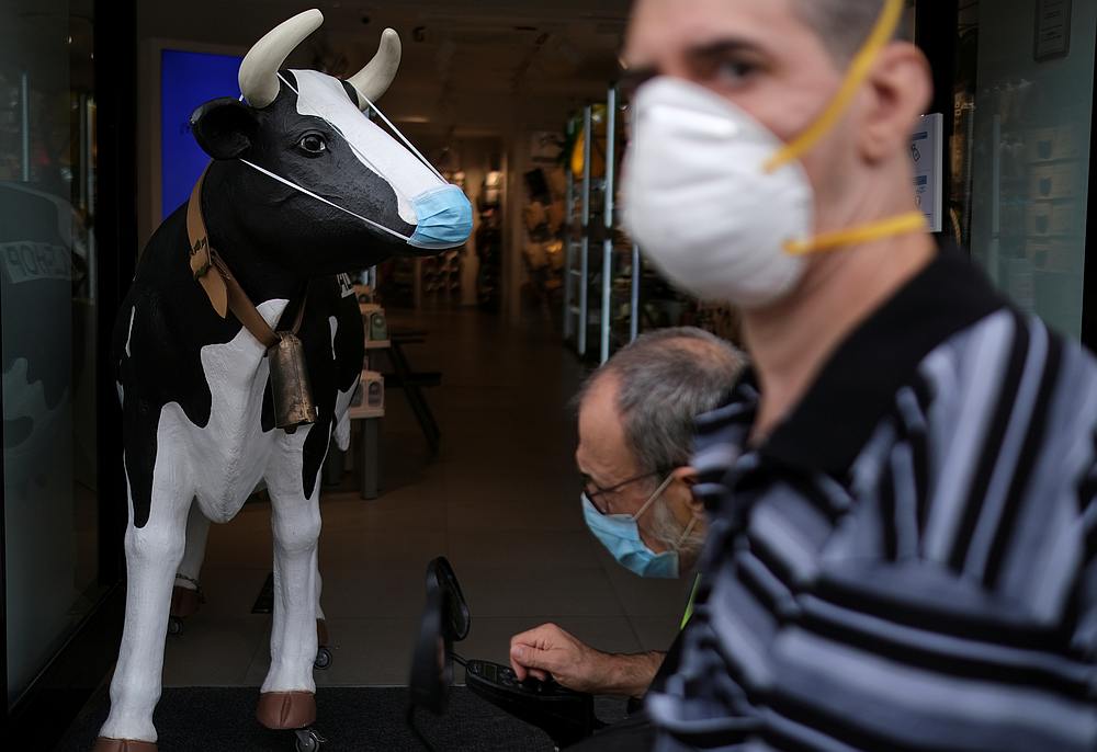 Men wearing face masks walk past a figure of a cow wearing a protective mask outside a shop, amid the Covid-19 outbreak in Barcelona, Spain August 4, 2020. u00e2u20acu201d Reuters pic