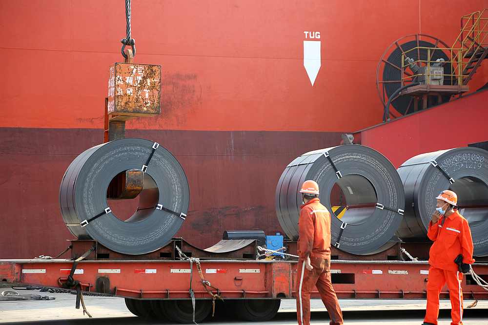 Workers wearing face masks following the Covid-19 outbreak load steel products for export to a cargo ship at a port in Lianyungang, Jiangsu province, China May 27, 2020. u00e2u20acu201d China Daily pic via Reuters