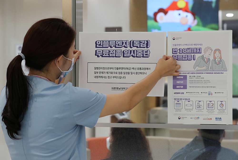 A health worker attaches a notice for suspension of influenza vaccination programmes on an entrance of a hospital in Sejong, South Korea September 22, 2020. u00e2u20acu201d Yonhap pic via Reuters