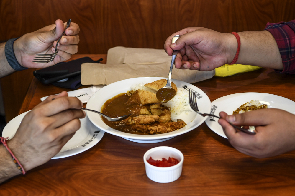 Customers eat sitting at a table at CoCo Ichibanya Japanese curry chain restaurant in Gurgaon on the outskirts of New Delhi. — AFP pic