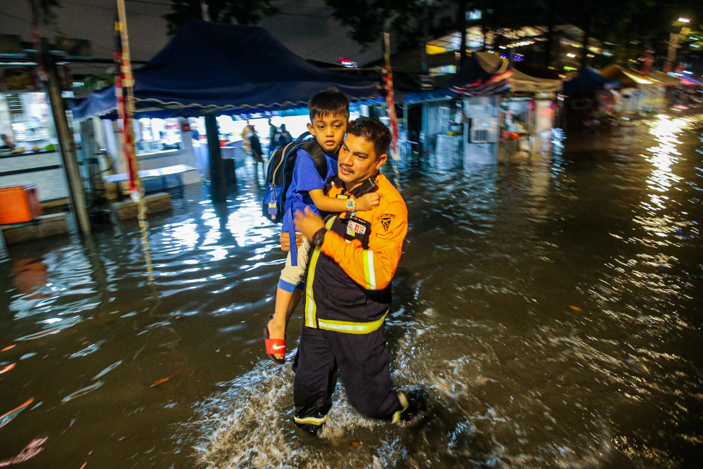 A man carries a boy as he wades through flood water in Kampung Baru September 10, 2020. 