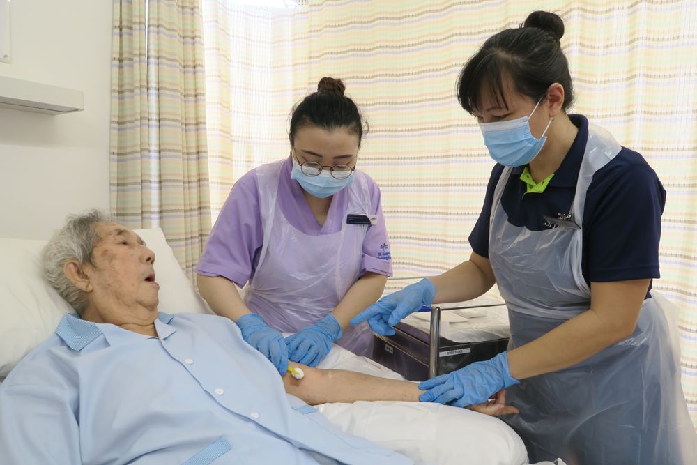Caroline Tan (right) providing on-the-job wound care training for Naqiyah Yusuf (centre), a staff nurse at St Andrew’s Nursing Home (Taman Jurong). — St Andrew’s Nursing Home picture via TODAY