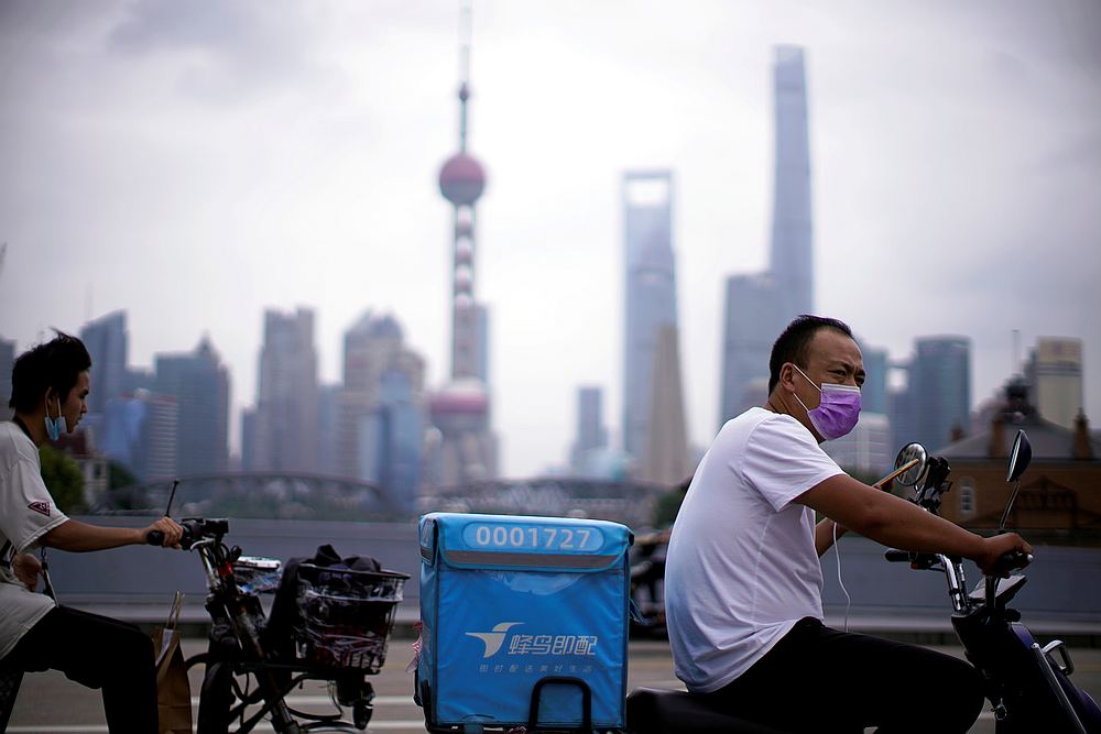 Delivery workers wearing face masks ride scooters in front of Lujiazui financial district, in Shanghai, following the Covid-19 outbreak, China July 10, 2020. u00e2u20acu201d Reuters pic