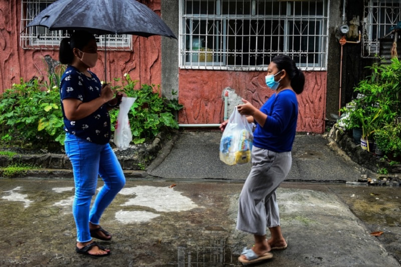 Lorraine Ann Imperio (left) carrying a bag of old milk bottles as she meets with Reniel Bariso to barter their goods in Las Pinas City, suburban Manila. u00e2u20acu2022 AFP pic