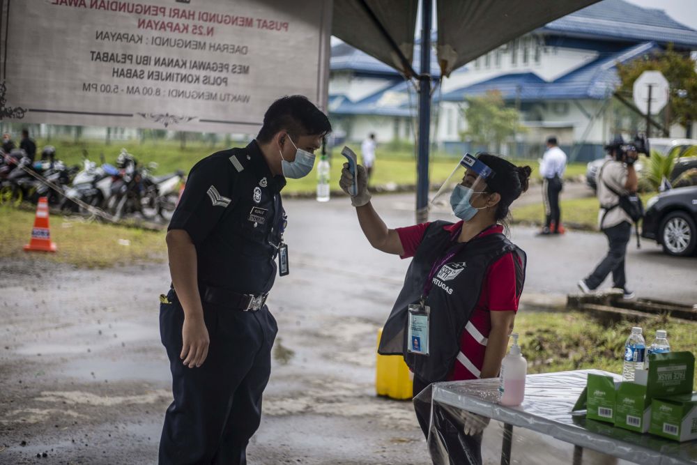 A police officer has his temperature taken before entering the voting centre at the Sabah Contingent police headquarters in Kota Kinabalu September 22, 2020. u00e2u20acu201d Picture by Firdaus Latif