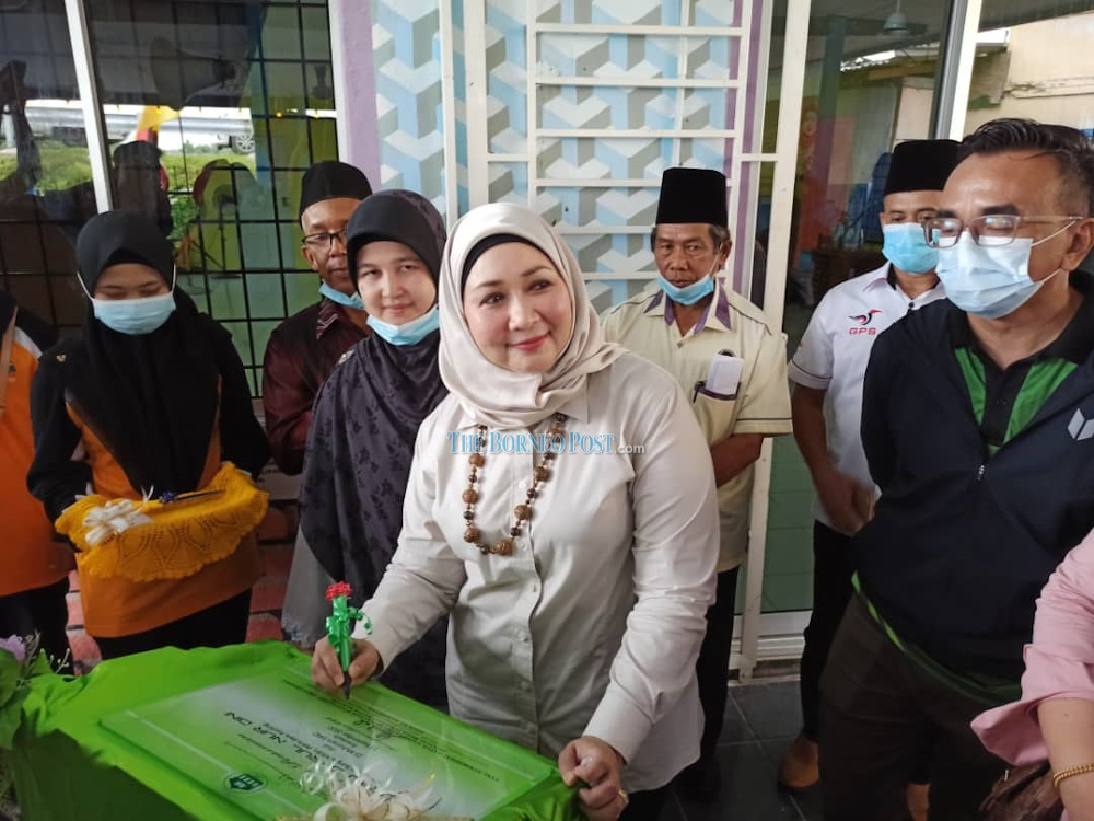 Sharifah Hasidah signing the surau plaque at the event. u00e2u20acu201d Borneo Post pic