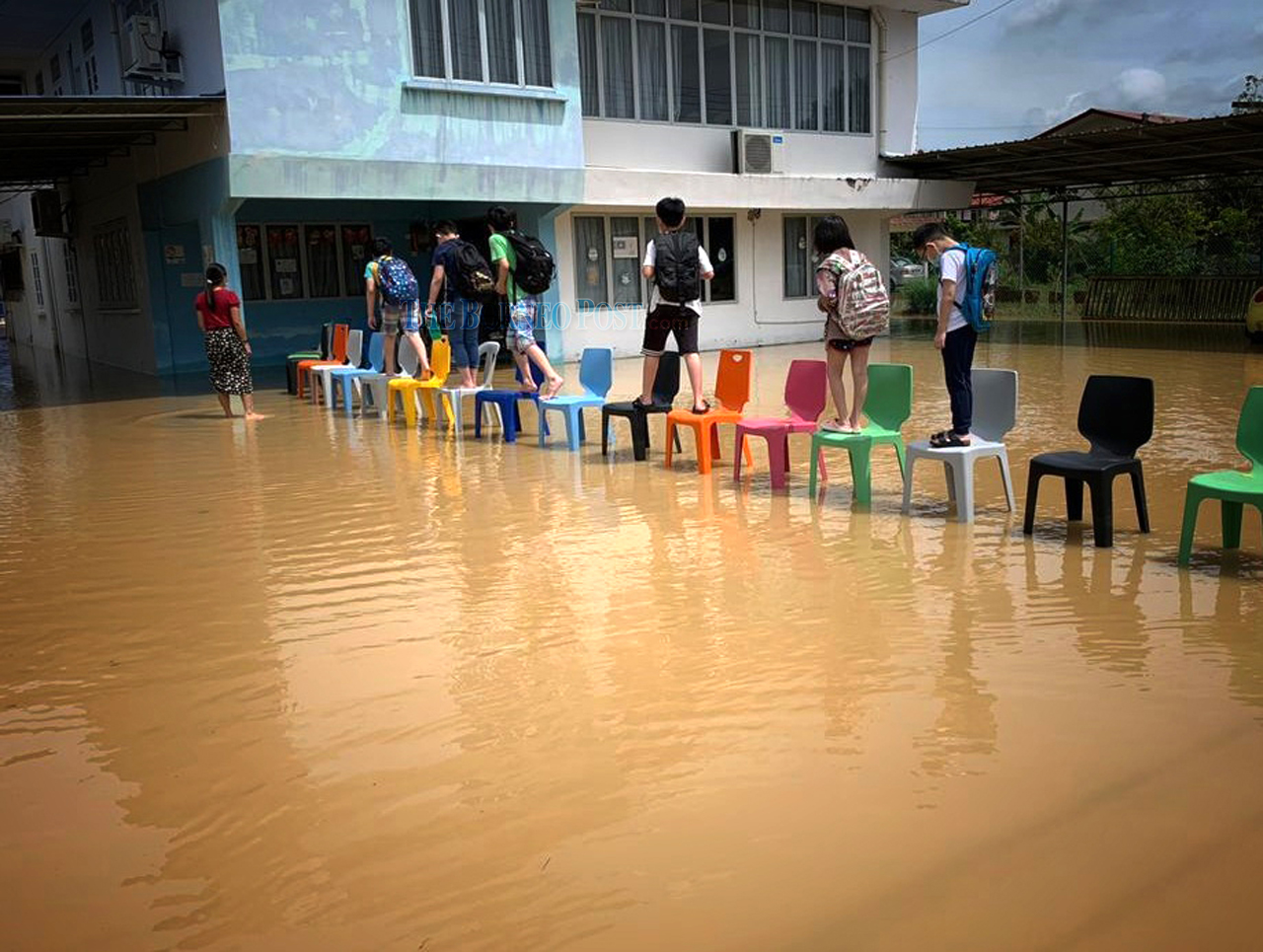School children walk on chairs to avoid getting wet. u00e2u20acu201d Picture via WhatsApp