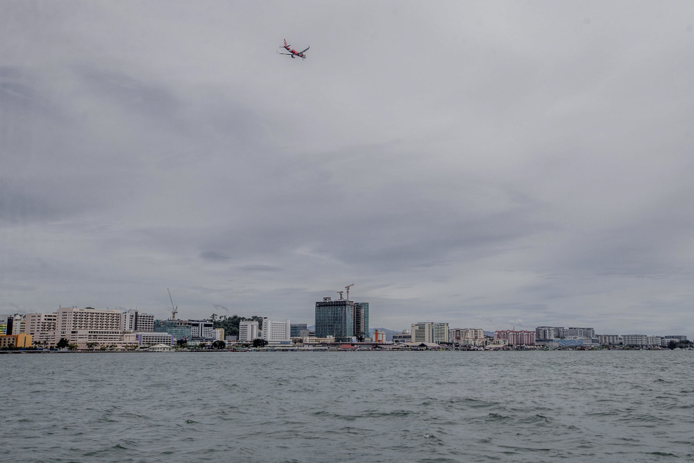 An AirAsia plane flies over the skyline of Kota Kinabalu September 30, 2020. u00e2u20acu201d Picture by Firdaus Latif 