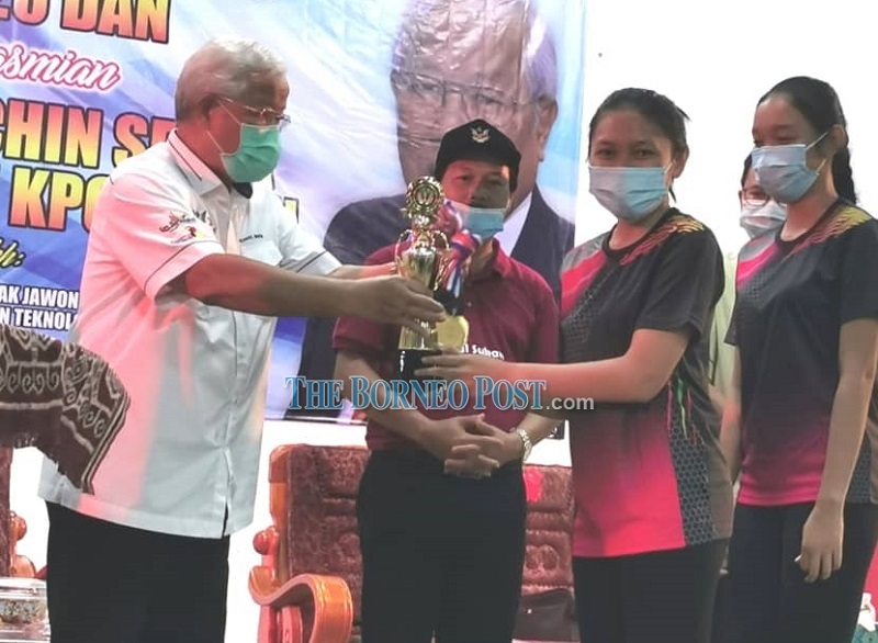 Education, Science and Technological Research Minister Datuk Sri Michael Manyin Jawong (left) hands over a trophy to members of Kampung Taee netball team who won the netball tournament. u00e2u20acu201d Borneo Post Online pic