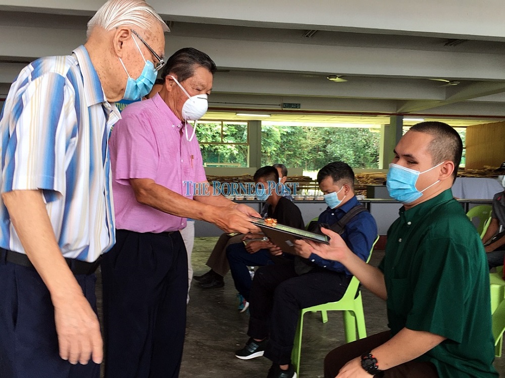 Dr Hsiung (second left) presents a certificate to one of the blind massage therapist graduates, accompanied by Ying (left). u00e2u20acu201d Borneo Post Online pic