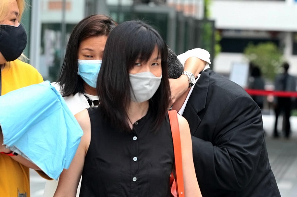 Mark Tan Teik Yu (second row, right, with head hidden) exiting the State Courts on October 12, 2020 while being shielded by family members and friends. u00e2u20acu201d TODAY pic