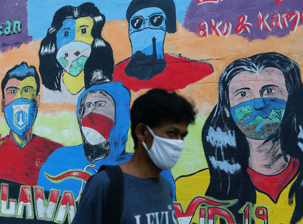 A man wearing a protective face walks past near a mural promoting awareness of the coronavirus disease outbreak in Jakarta, Indonesia, October 2, 2020. u00e2u20acu2022 Reuters pic