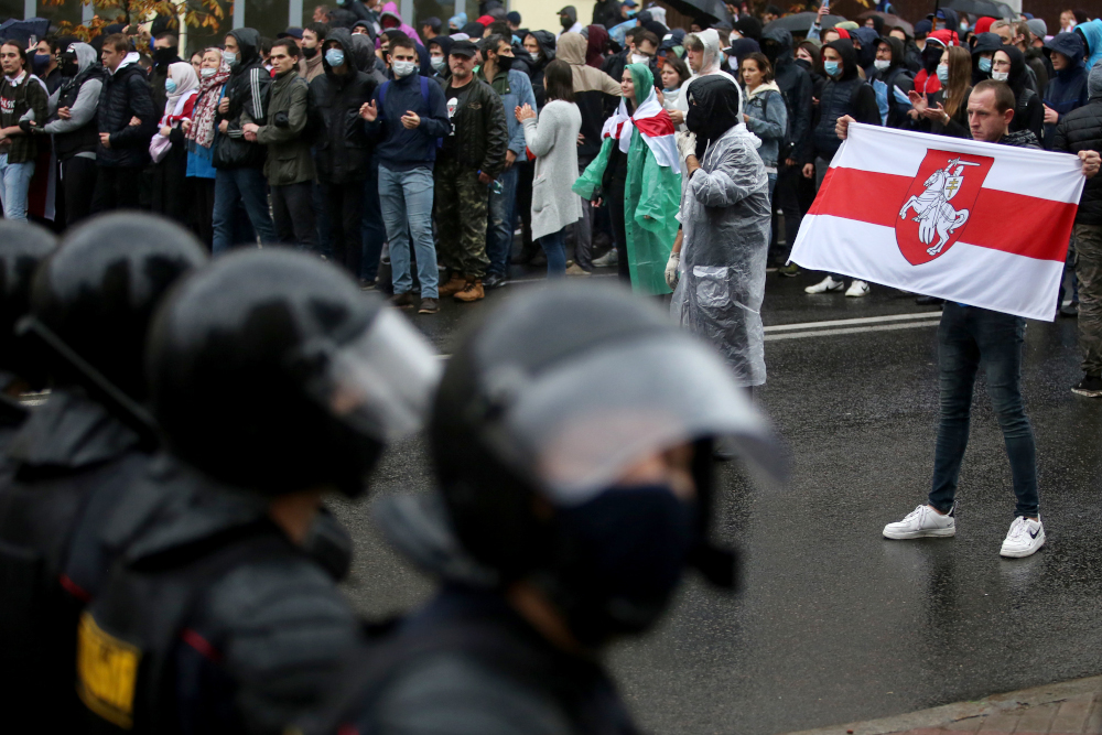 A man carrying a former white-red-white flag of Belarus stands in front of law enforcement officers during a rally to protest against the Belarus presidential election results in Minsk on October 11, 2020. u00e2u20acu201d AFP pic