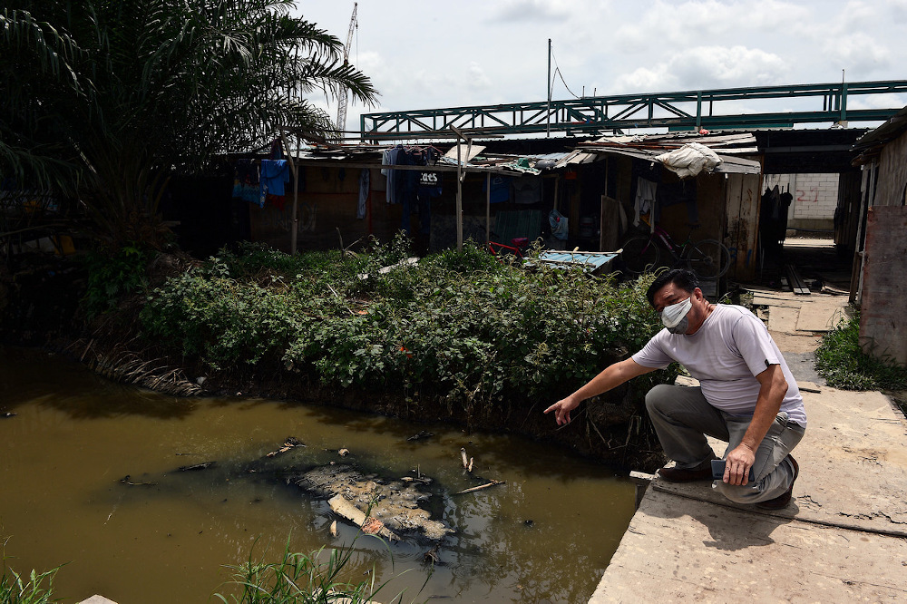A resident points to the waste dumped into Sungai Manggis October 17, 2020. u00e2u20acu201d Bernama pic
