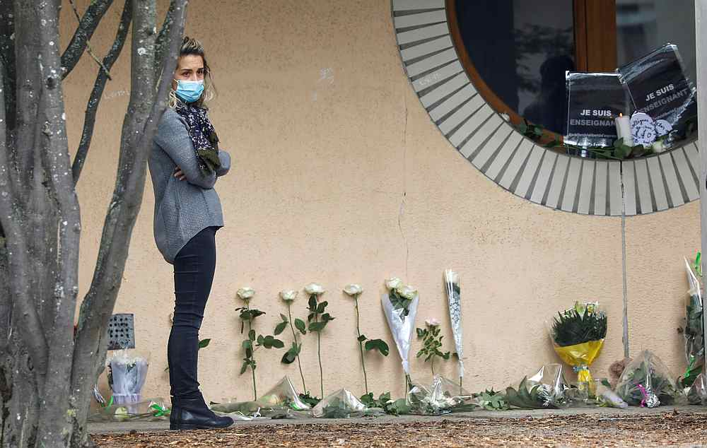 A woman stands next to flowers at the Bois d'Aulne college after the attack in the Paris suburb of Conflans St Honorine, France October 17, 2020. u00e2u20acu201d Reuters pic