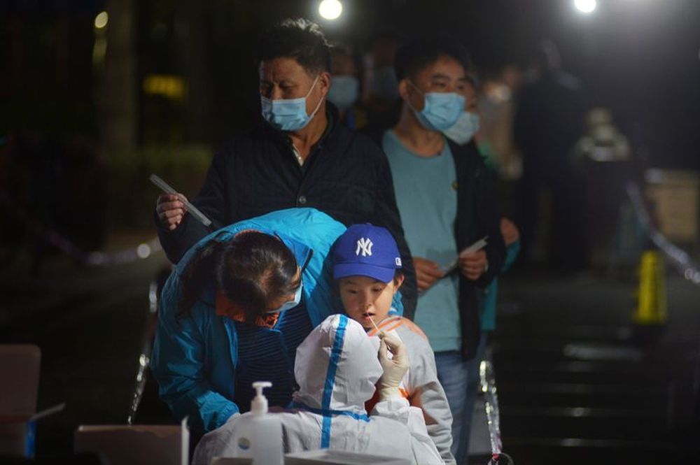 A medical worker in protective suit collects a swab from a child for nucleic acid testing, following new cases of coronavirus disease in Qingdao, Shandong province, China October 13, 2020. u00e2u20acu201d  cnsphoto via Reuters