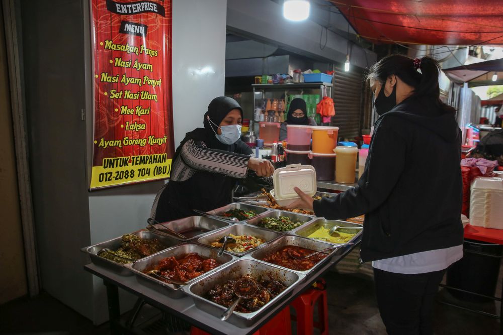 Dewi Kudrawati (left) serves a customer at her mixed-rice stall in Kuala Lumpur October 14, 2020. u00e2u20acu201d Picture by Yusof Mat Isa