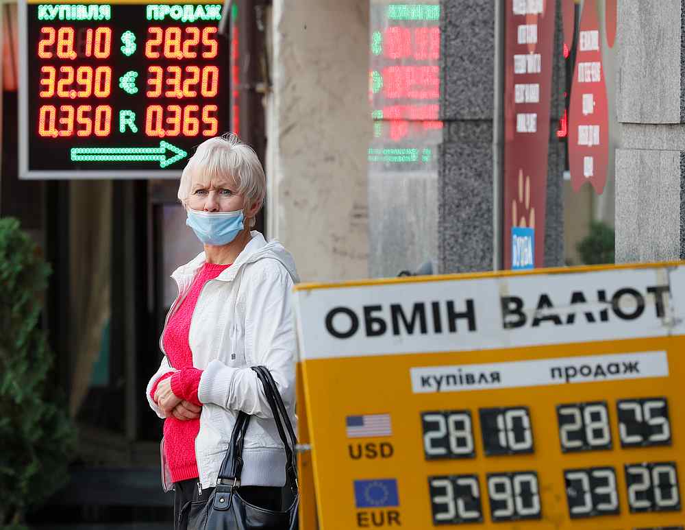 A woman wearing a protective face mask, used as a preventive measure against Covid-19, stands near a currency exchange office in central Kyiv, Ukraine October 9, 2020. u00e2u20acu201d Reuters pic