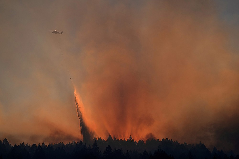 A helicopter is backlit by the sun setting as it drops water over the Bothe-Napa Valley State Park alight from the Glass Fire in Calistoga, California October 3, 2020. u00e2u20acu201d Reuters pic